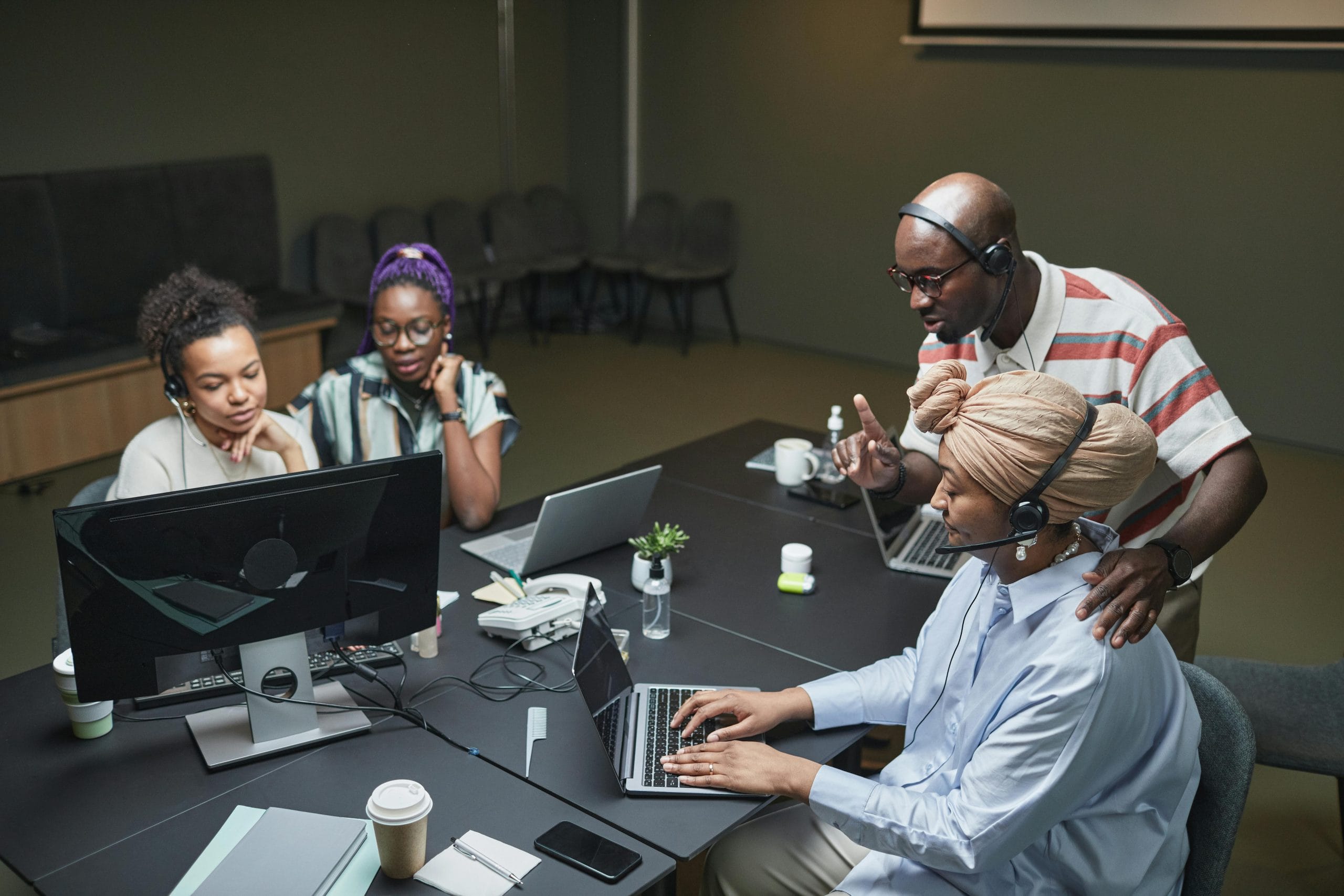 Team of coworkers in an office call center collaborating and using laptops.